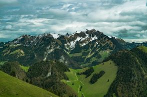 a view of a mountain range with green grass and trees