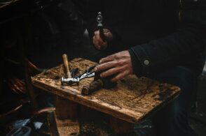 a man is using a pair of scissors to cut a piece of wood